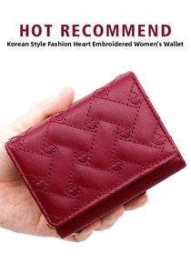 Detailed hand-held view of the wine red tri-fold wallet with heart embroidery and quilting