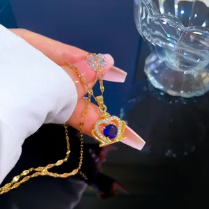 Detailed close-up of a gold crown pendant necklace with blue gemstone and white zircons