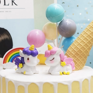 Close-up of cute resin unicorn figures with rainbow and balloon cake decorations
