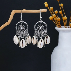 Detail of bohemian dreamcatcher earrings with silver metal frame and white shell feathers