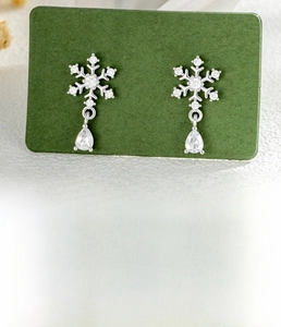 Macro shot of silver snowflake ear stud with zircon water drop pendant and steel bar detail