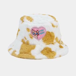 Detail of plush cow print bucket hat featuring pink heart patch with cat embroidery