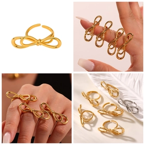 Detail view of adjustable bow rings in gold and silver finish on hand with feathers