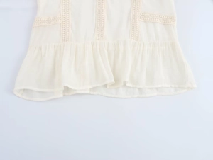 Detailed view of delicate lace patchwork and ruffled hem on a white long-sleeve blouse