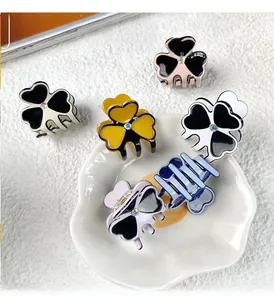 Detailed view of small acetate clover hair clips in pastel colors with central rhinestones
