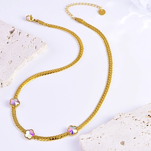 Golden snake chain necklace with three iridescent flower pendants on white stone background