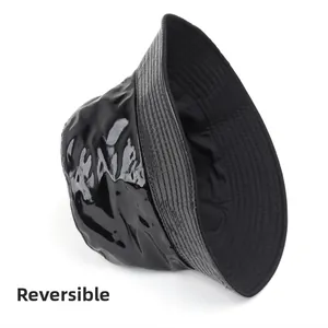Detail of reversible bucket hat showing contrast between glossy patent leather and matte twill