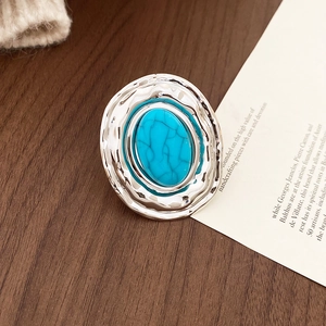 Dettaglio dell'anello d'argento ondulato con pietra turchese blu su legno caldo
