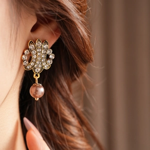 Close-up of vintage gold flower earring with sparkling diamond and pink pearl pendant