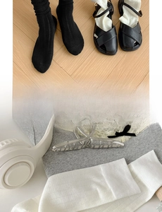 Flat lay of gray cotton crew socks with matte black Mary Jane shoes and hair clip