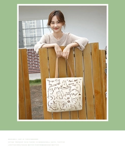Detail of off-white canvas tote bag featuring brown cat illustrations and sturdy webbing handles