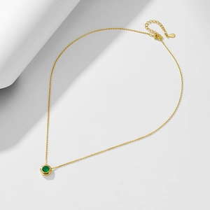 Macro shot of s925 silver gold-plated necklace with a round green agate stone pendant