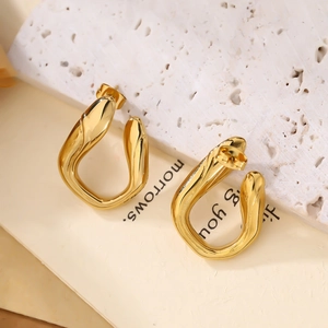 Macro detail of irregular U-shape gold-plated earrings with organic twisted design