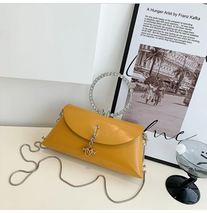 Detail of yellow leather handbag with rhinestone ring handle and silver metal chain strap