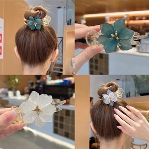 Detail of floral chiffon hair clips in dark green and cream white with gold stamens