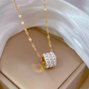 Detail of a gold cylinder pendant with triple crystal rings on silk background