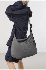 Side view of large charcoal grey nylon crossbody bag on model with adjustable strap