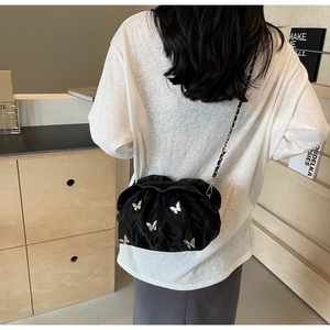 Detail of a black pleated cloud bag featuring silver butterfly accents and chain strap