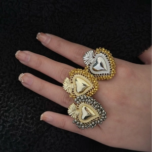 Anelli vintage cuore sacro oro e argento indossati su un elegante sfondo nero