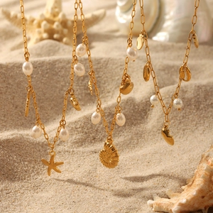 Detailed close-up of golden necklaces with starfish, shell charms and white pearls