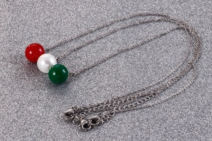 Détail macro du collier en titane avec pendentifs sphériques rouges, blancs et verts