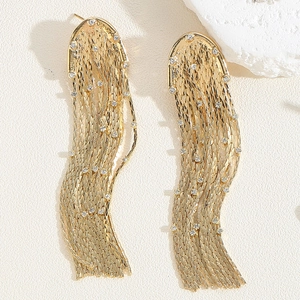 Detailed macro of golden chain tassel earrings with white zircons on a textured surface