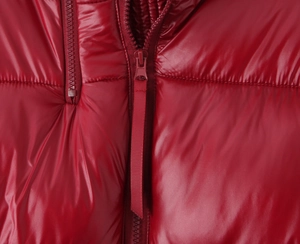 Detail of red glossy puffer jacket featuring high-neck collar and high-quality zipper closure