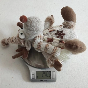 Weight measurement of a plush reindeer Christmas ornament on a kitchen scale showing 240.5g