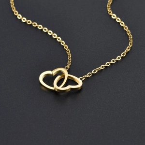 Polished titanium steel double heart necklace in gold finish on dark background