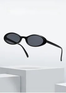 Close-up of stylish black oval sunglasses displayed on modern white geometric blocks