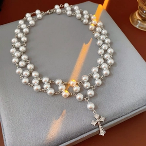 Close-up of double-layer pearl choker with silver cross pendant on velvet box