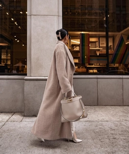 Détail du manteau en peluche avoine avec sac à main en cuir dans un décor urbain chic