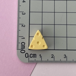 Miniature resin cheese charm measured with a ruler for DIY crafts size reference