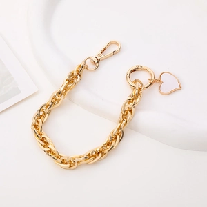 Detailed view of a gold metal phone chain with a heart pendant and lobster clasp detail