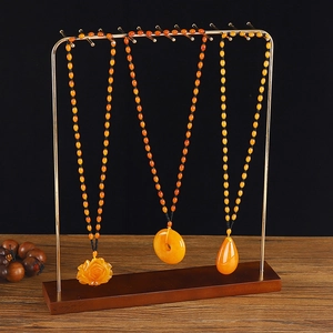 Three amber pendant necklaces displayed on premium wood and gold metal jewelry stands