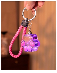 Close-up of a pink and purple cat paw shaker keychain with liquid glitter and braided strap