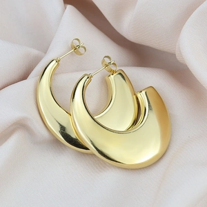 Macro shot of thick gold C-shaped hoop earrings with polished metallic mirror finish on satin
