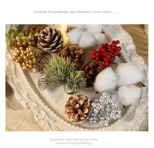 Close-up of Christmas pine cones, red berries, and cotton flowers on a ceramic tray