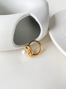 Vue rapprochée d'une bague dorée multicouche avec perle blanche sur céramique