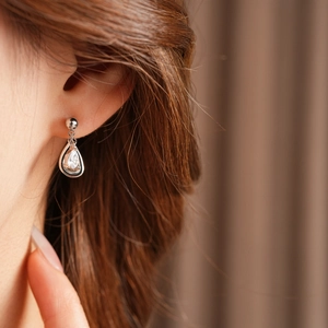 Close-up of sparkling waterdrop zircon earring on model's ear with silver needle detail