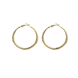Pair of minimalist golden round hoop earrings with polished metallic finish on white background