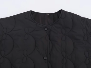 Détail de la veste matelassée noire avec col rond et fermeture par boutons-pression