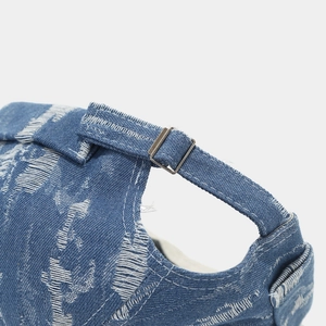Detail of vintage blue denim docker hat showing distressed textures and metal buckle