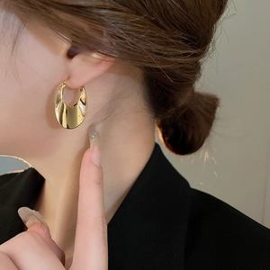 Polished gold U-shaped oval hoop earrings shown on model for a minimalist fashion look