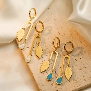 Gold leaf drop earrings with white shell and turquoise pendants on a white silk backdrop
