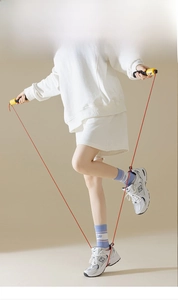 Athletic woman in white sports set wearing light blue crew socks with a jump rope