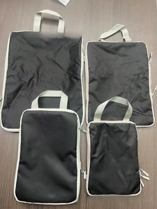 Close-up of four black nylon compression packing cubes with grey trim and handles