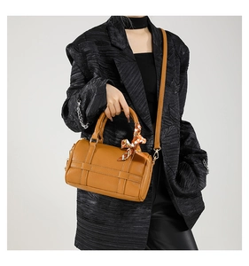 Detail view of brown Boston barrel bag with patterned silk scarf and long strap