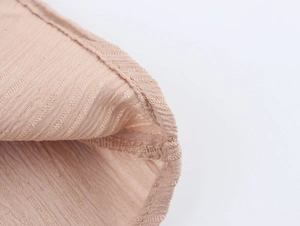 Gros plan détaillé d'un tissu pêche texturé avec motifs côtelés et coutures d'ourlet fines