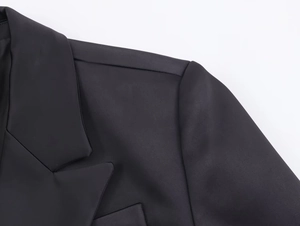 Detail shot of the shoulder and lapel on a black herringbone wool blazer for women